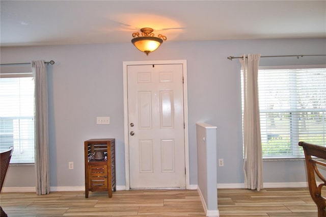 entryway with light wood finished floors, baseboards, and a wealth of natural light