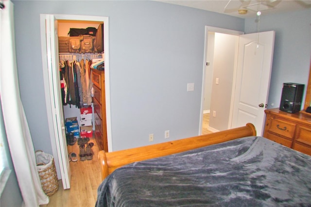 bedroom with a closet, a walk in closet, and wood finished floors