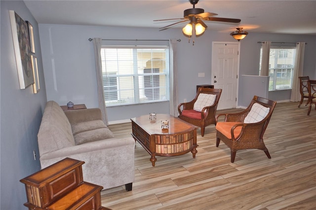 living area featuring light wood-type flooring, baseboards, and a ceiling fan