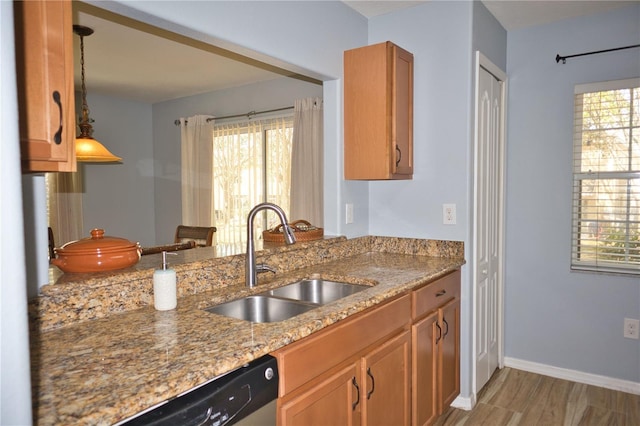 kitchen featuring a sink, baseboards, light wood-style floors, stainless steel dishwasher, and light stone countertops