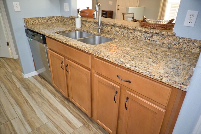 kitchen featuring stainless steel dishwasher, wood tiled floor, light stone counters, and a sink