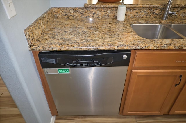 interior details with dishwasher, light wood finished floors, a sink, and light stone countertops