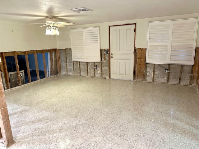 living area featuring ceiling fan, visible vents, and speckled floor