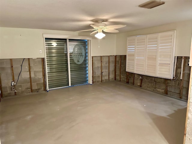 unfurnished room with concrete block wall, ceiling fan, visible vents, and concrete flooring