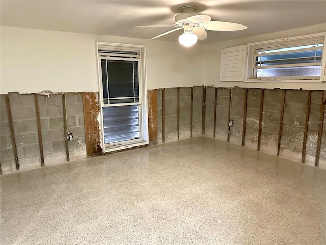 empty room with ceiling fan and speckled floor