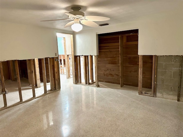 empty room featuring ceiling fan, visible vents, and speckled floor