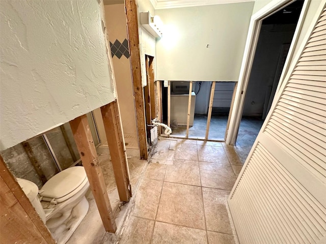 bathroom featuring tile patterned flooring, crown molding, and a textured wall