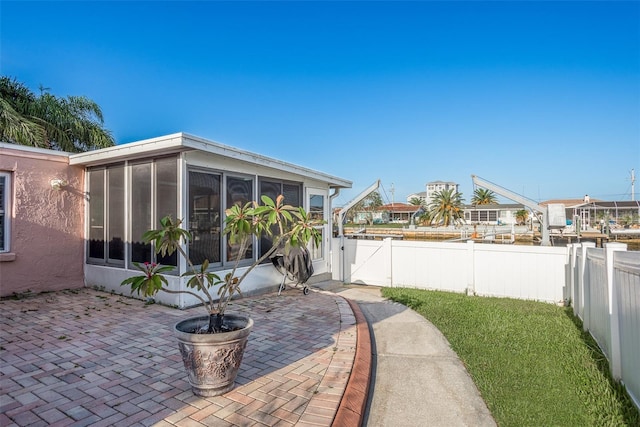 view of patio / terrace featuring a sunroom and fence