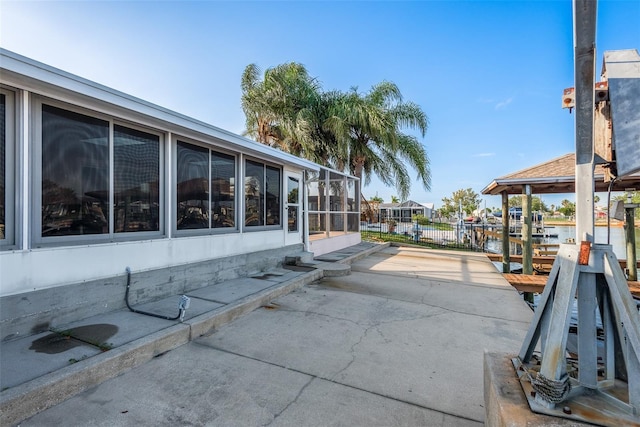 exterior space featuring a water view, boat lift, a dock, and a patio