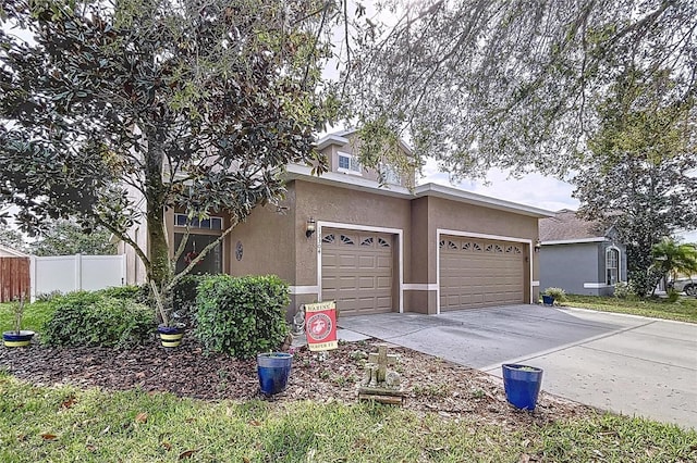 view of front of property featuring driveway, fence, and stucco siding