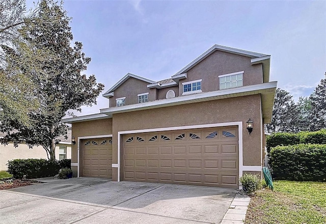 view of front facade featuring driveway, an attached garage, and stucco siding