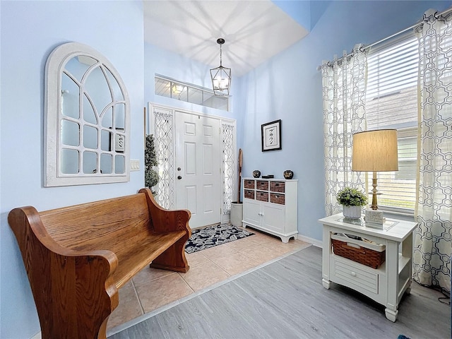 entryway featuring baseboards, a chandelier, wood finished floors, and a healthy amount of sunlight