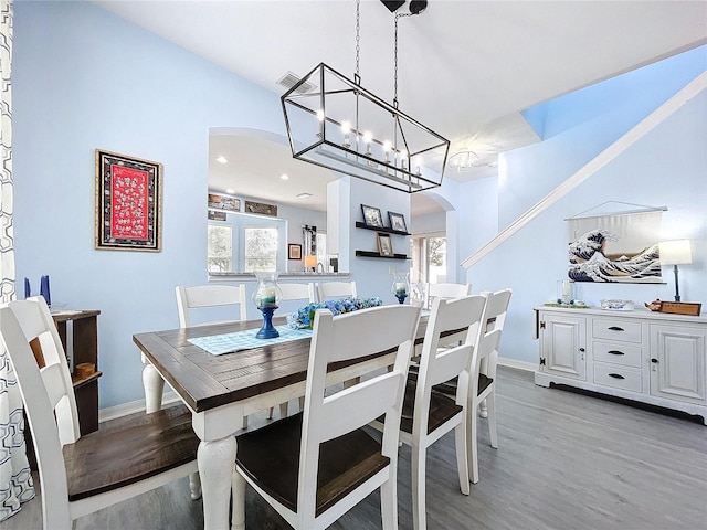 dining area featuring light wood-type flooring, arched walkways, visible vents, and baseboards