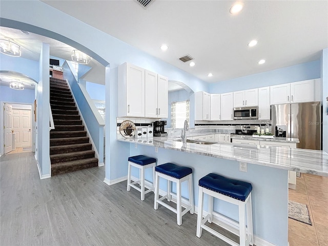 kitchen featuring arched walkways, a breakfast bar, stainless steel appliances, tasteful backsplash, and a sink