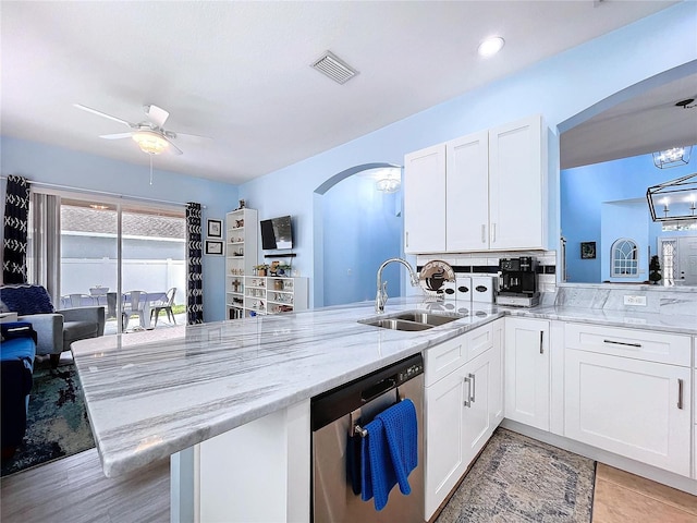 kitchen featuring visible vents, arched walkways, a peninsula, stainless steel dishwasher, and a sink