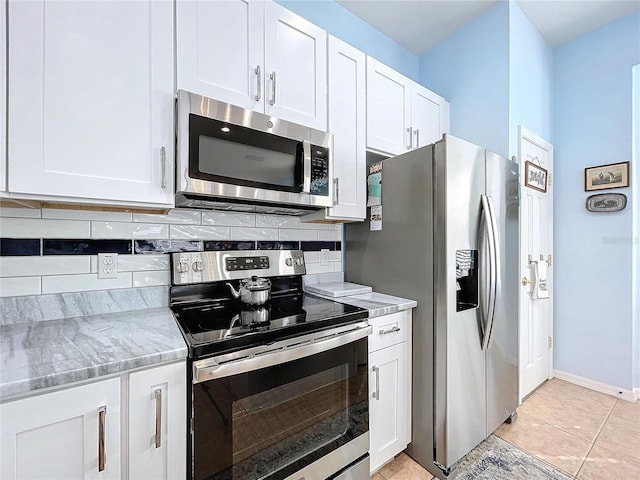 kitchen with light stone counters, light tile patterned floors, decorative backsplash, appliances with stainless steel finishes, and white cabinets