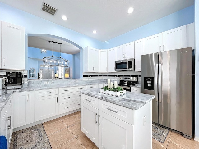 kitchen with stainless steel appliances, visible vents, light stone counters, and decorative backsplash