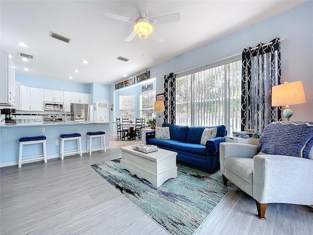 living area with ceiling fan, wood finished floors, and visible vents