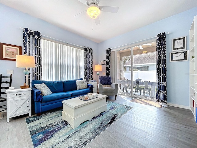 living room featuring a ceiling fan, baseboards, and wood finished floors