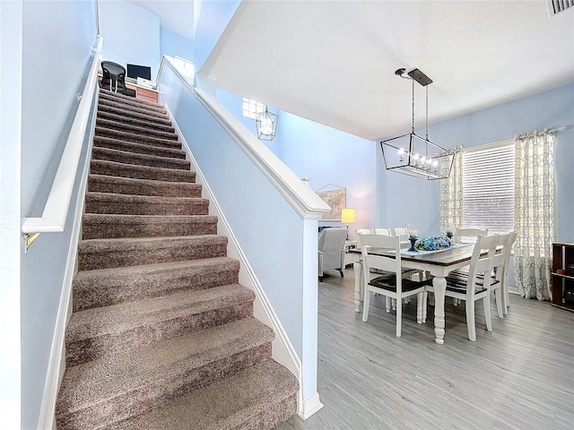 stairway featuring a wealth of natural light, visible vents, baseboards, and wood finished floors