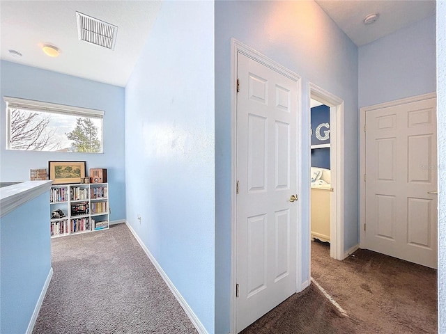 hallway featuring carpet, visible vents, and baseboards