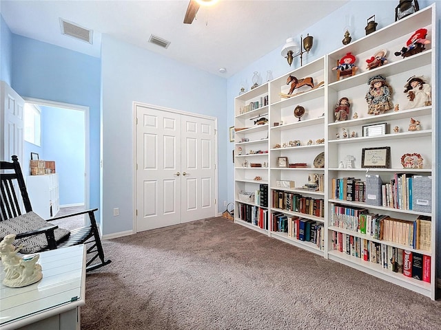 living area with carpet floors, visible vents, and a ceiling fan