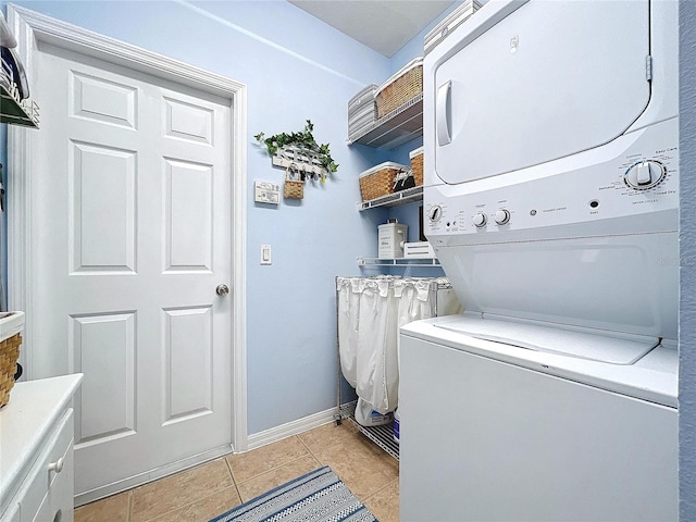 laundry room with baseboards, light tile patterned flooring, cabinet space, and stacked washer / drying machine