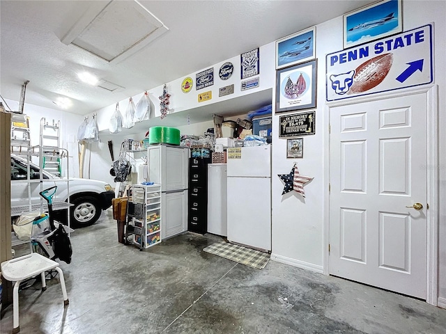 garage featuring baseboards and freestanding refrigerator