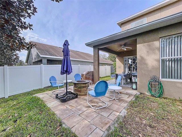 view of patio featuring a fenced backyard, a fire pit, and a ceiling fan