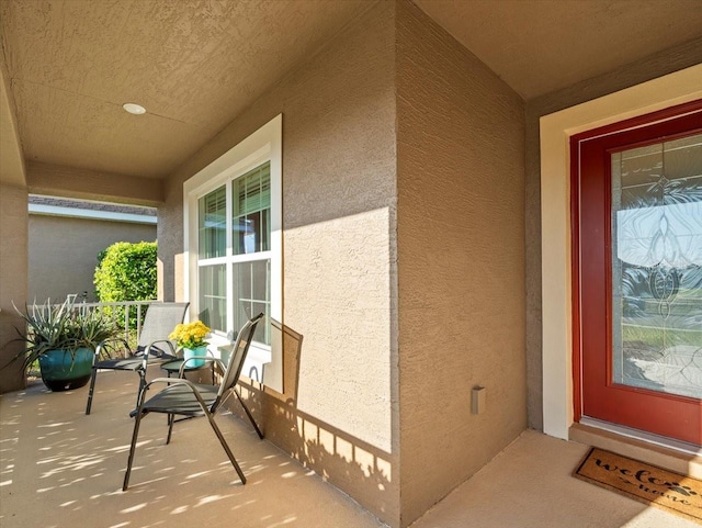 view of exterior entry with covered porch and stucco siding