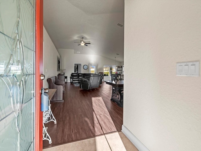 interior space featuring visible vents, a ceiling fan, a textured wall, wood finished floors, and vaulted ceiling