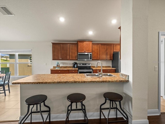 kitchen featuring stainless steel appliances, a breakfast bar, a sink, and visible vents