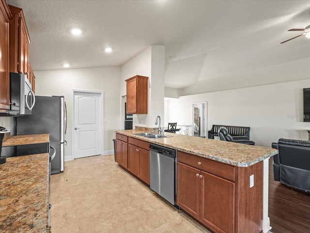 kitchen with a peninsula, a sink, open floor plan, vaulted ceiling, and appliances with stainless steel finishes