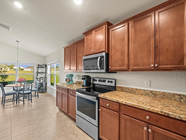 kitchen with lofted ceiling, appliances with stainless steel finishes, and light stone countertops