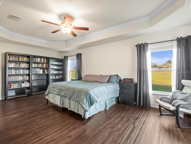 bedroom featuring wood finished floors, a raised ceiling, visible vents, and multiple windows