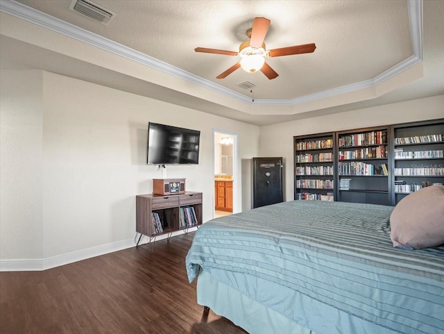 bedroom featuring dark wood-type flooring, a raised ceiling, visible vents, and ornamental molding