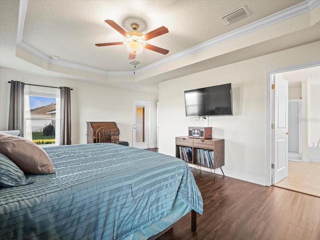 bedroom featuring crown molding, visible vents, a raised ceiling, and wood finished floors