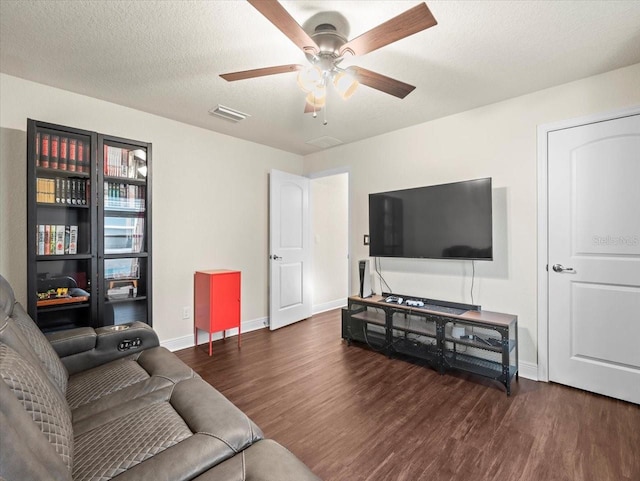 living area with a textured ceiling, baseboards, and wood finished floors