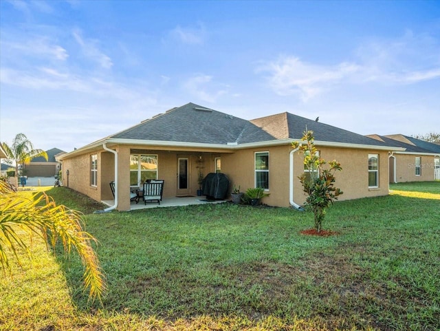 back of house with a yard, a shingled roof, stucco siding, and a patio