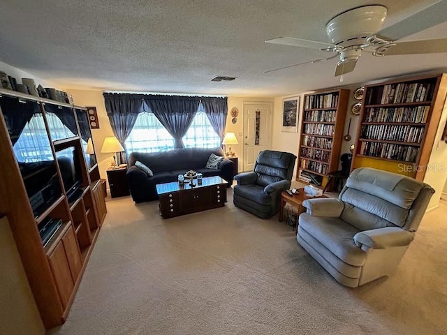 carpeted living room featuring a ceiling fan and a textured ceiling