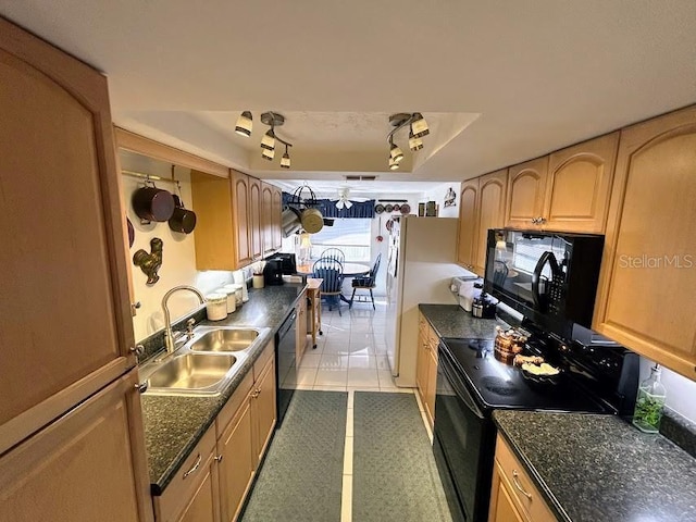 kitchen with light tile patterned floors, a sink, black appliances, a tray ceiling, and rail lighting