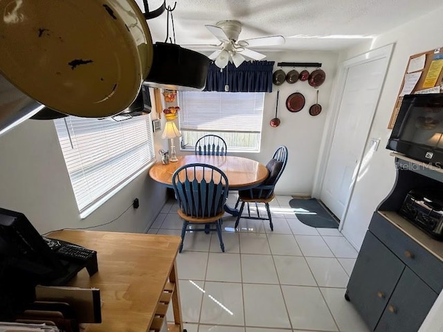 dining area with light tile patterned flooring, ceiling fan, and a textured ceiling