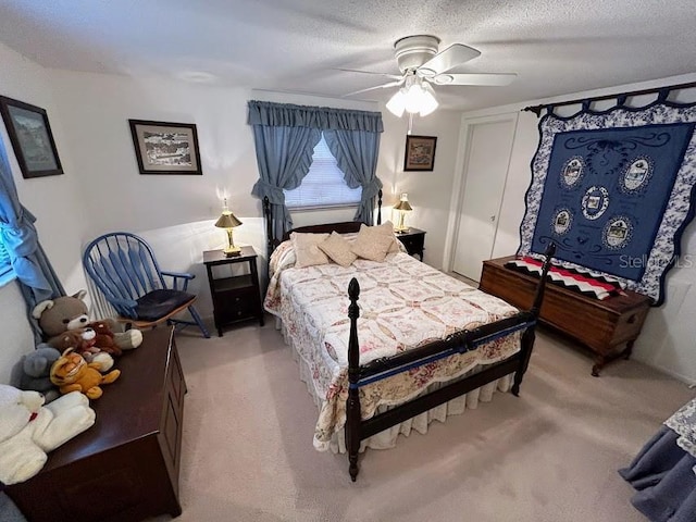 bedroom featuring light carpet, ceiling fan, and a textured ceiling