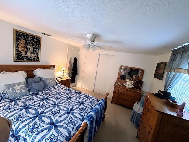 carpeted bedroom featuring a textured ceiling, a closet, visible vents, and a ceiling fan