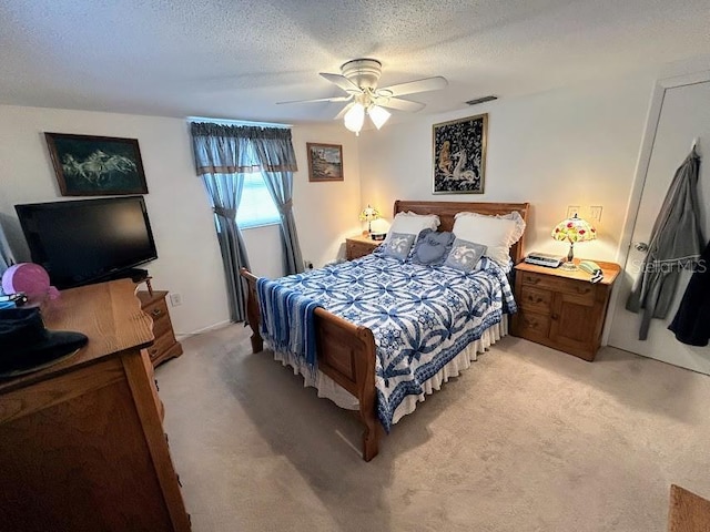 bedroom with light carpet, ceiling fan, visible vents, and a textured ceiling