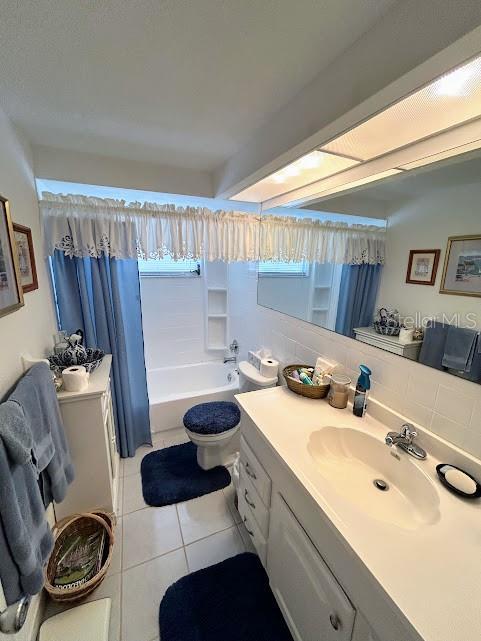 bathroom featuring toilet, vanity, decorative backsplash, and tile patterned floors