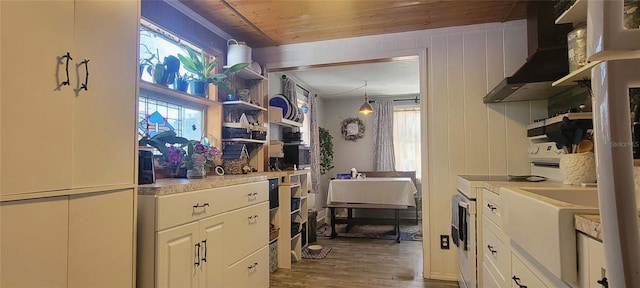 kitchen featuring white cabinetry, light countertops, wall chimney range hood, hanging light fixtures, and electric stove