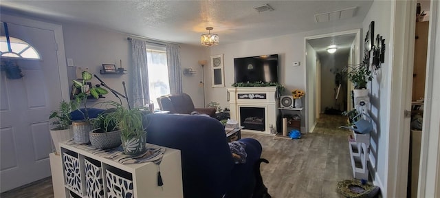 living room with a textured ceiling, a fireplace, wood finished floors, and visible vents