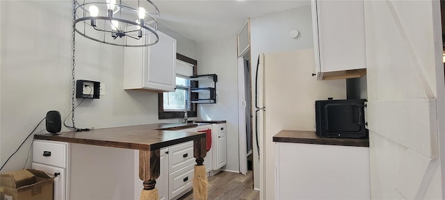 kitchen with light wood finished floors, white cabinetry, and pendant lighting