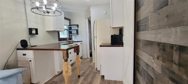 kitchen with hanging light fixtures, wood finished floors, wood counters, and white cabinets